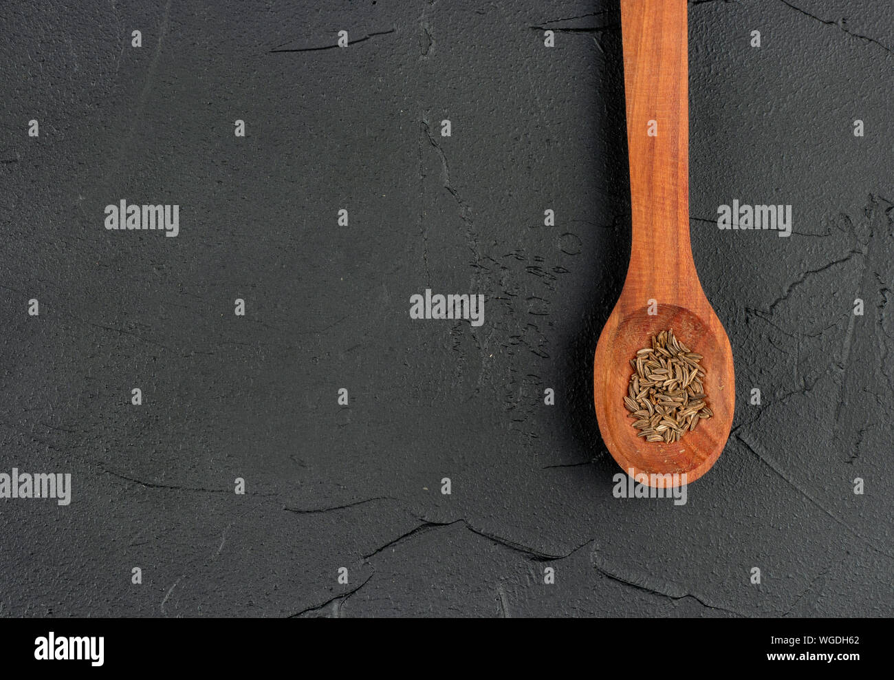 Gewürz trocknen Kümmel in hölzernen Löffel auf leeren dunklen Hintergrund closeup Stockfoto