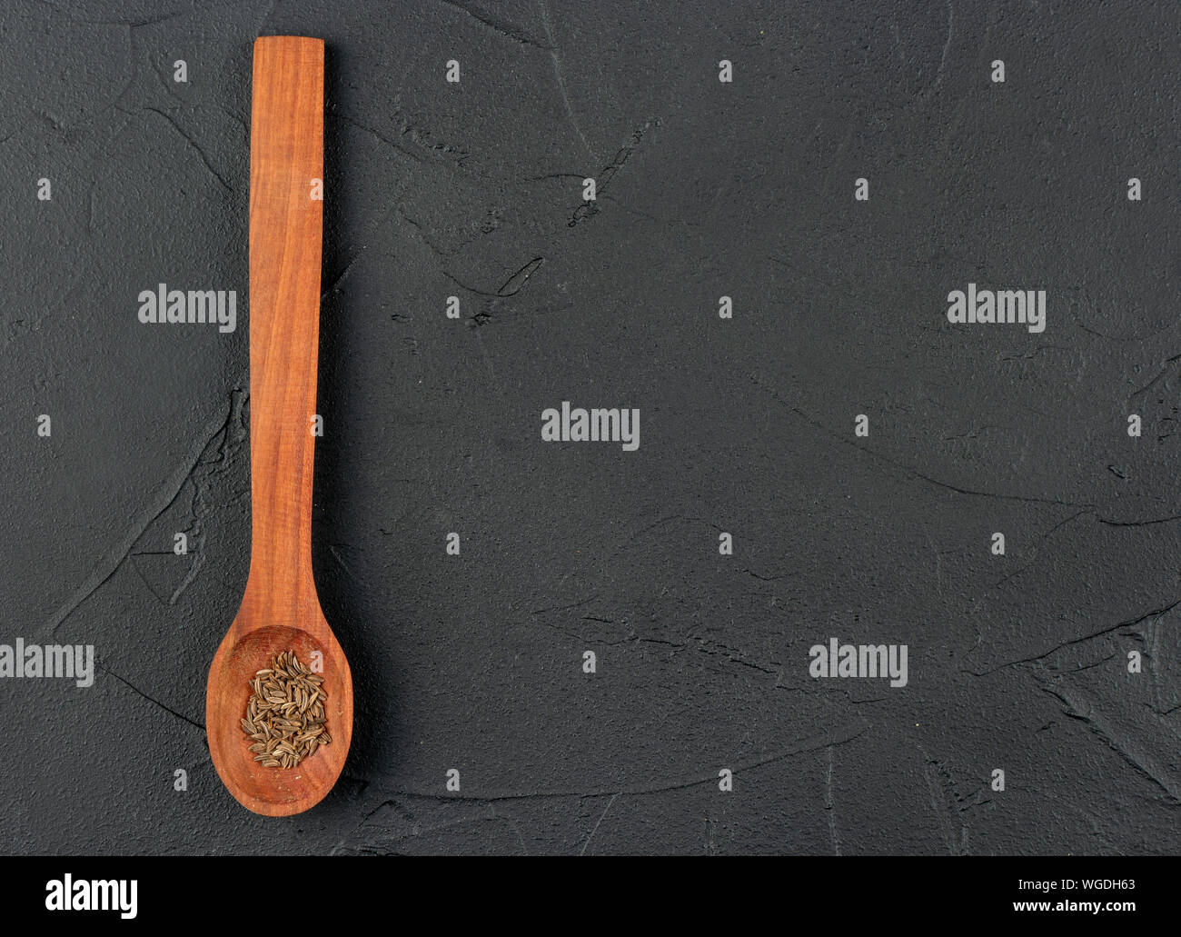 Gewürz trocknen Kümmel in hölzernen Löffel auf leeren dunklen Hintergrund Stockfoto