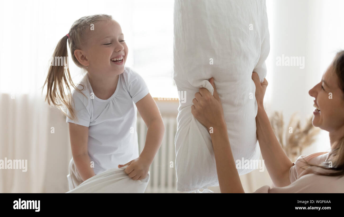 Fröhliche Mutter und Tochter holding Kissen auf dem Bett kämpfen Stockfoto