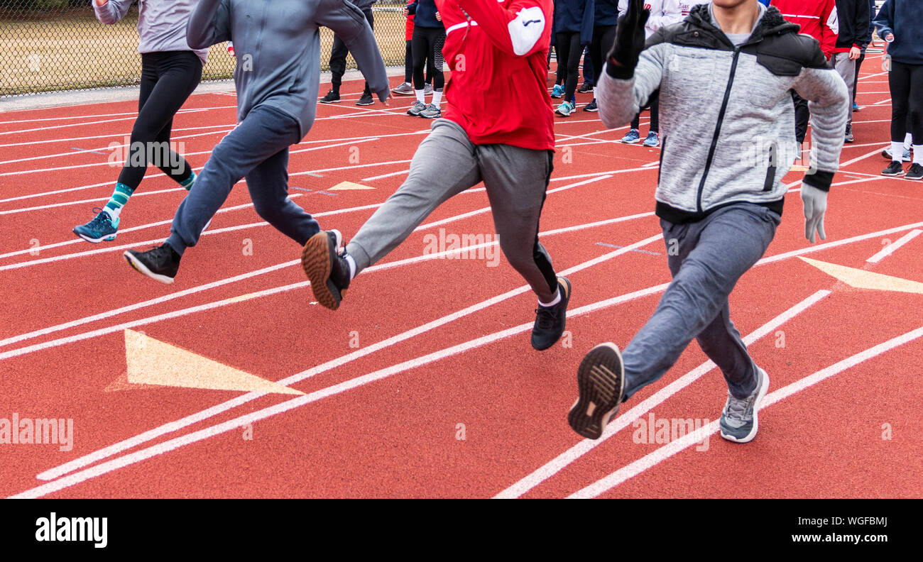 Ein High School track Team Straight Leg bounding Bohrer auf eine rote Spur im Winter üben. Stockfoto