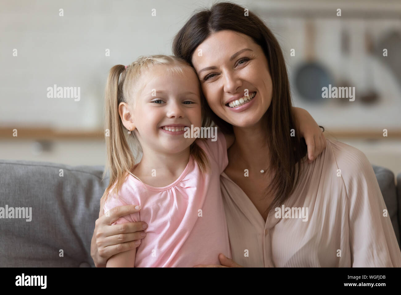 Schöne Mutter hug Tochter Familie sitzt innen bei Kamera suchen Stockfoto