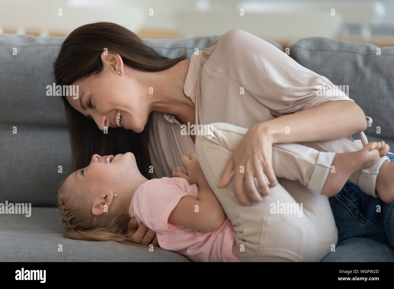 Bild fröhliche Mutter Nahaufnahme umfasst kitzelt kleine Tochter Stockfoto