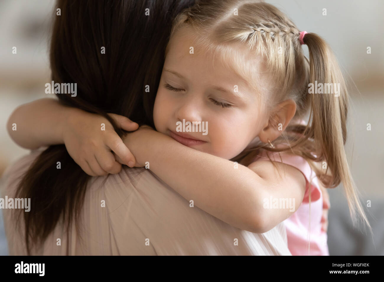 Detailansicht entzückende Tochter geschlossenen Augen umarmt liebevolle Mutter Stockfoto