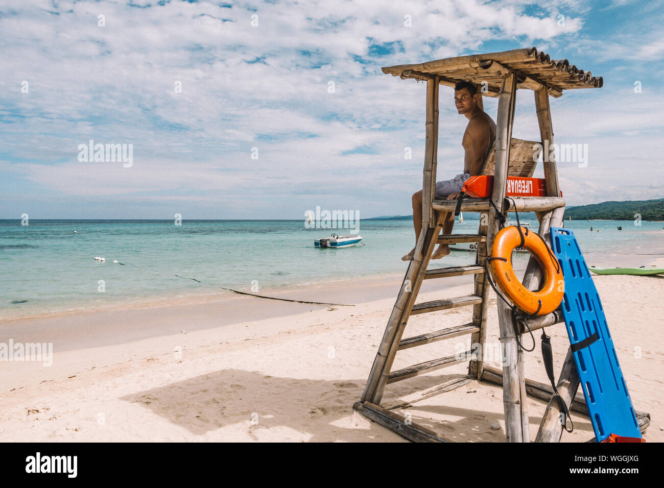 Mann sitzt auf Bademeister Stuhl am Strand gegen Sky Stockfotografie - Alamy