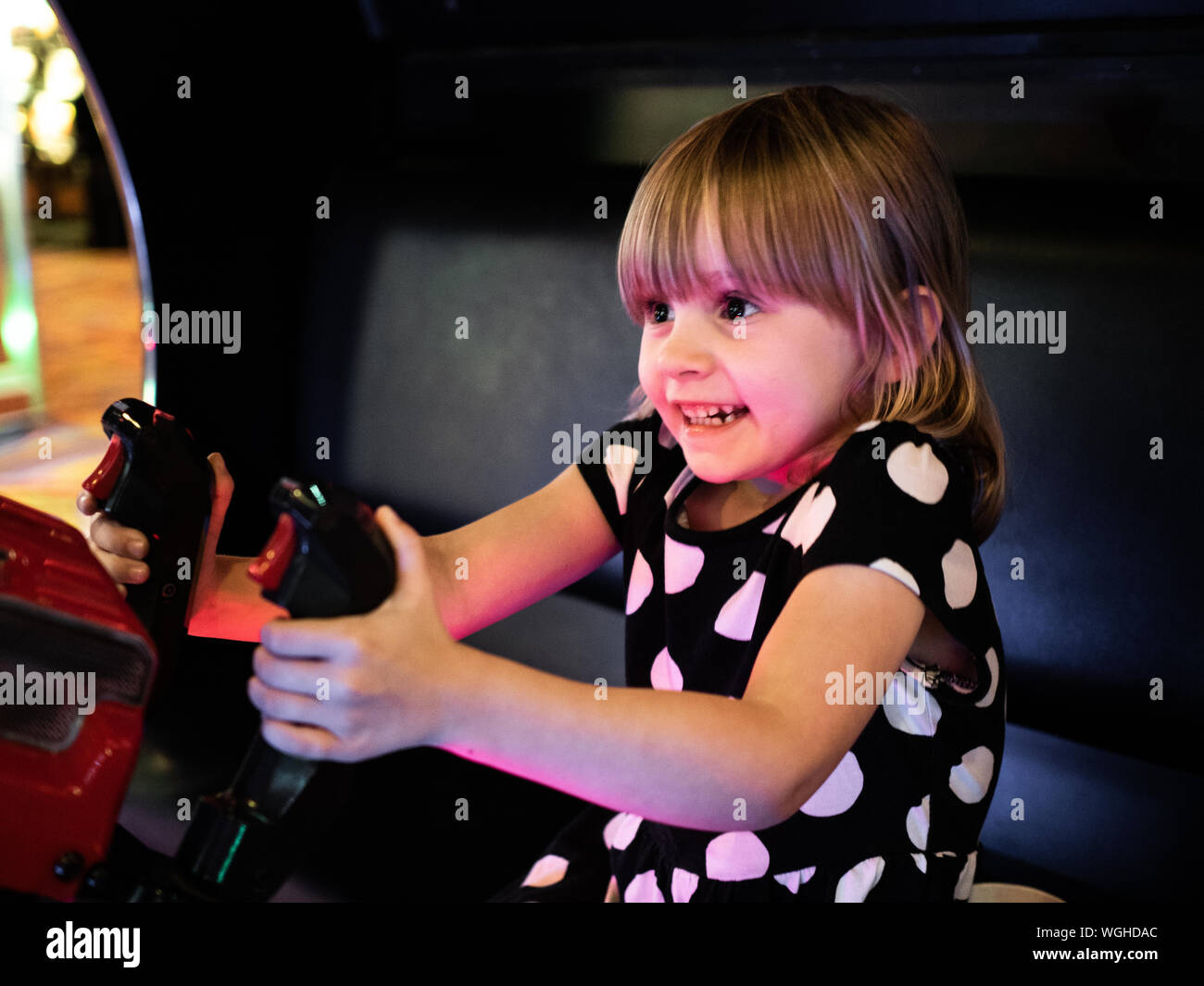 4 Jahre altes Spiel spielt Video Spiel im Arcade-modus an britischen Küstenort. Stockfoto