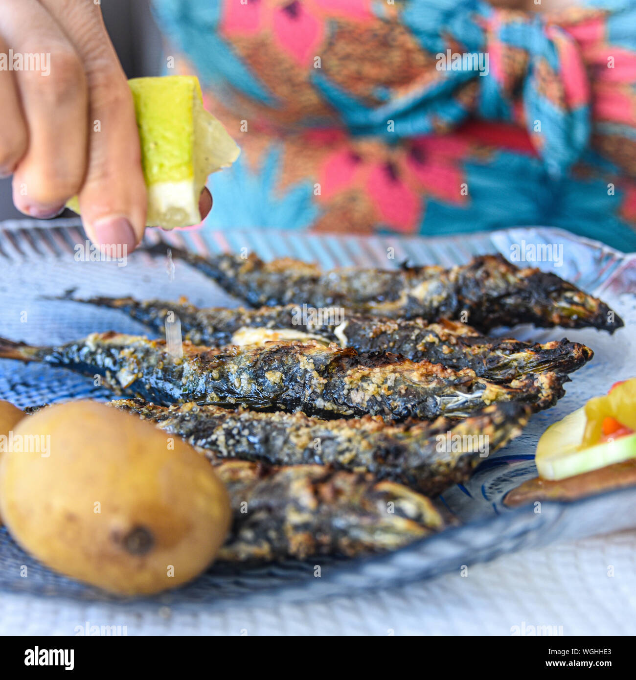 Lison, Portugal: ein Diner quetscht Zitronensaft frisch gegrillten Sardinen Stockfoto