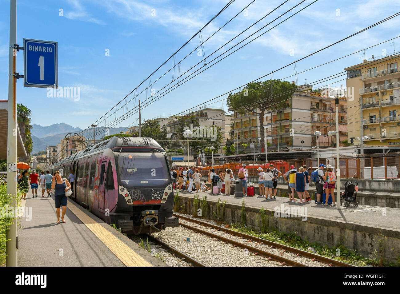 SORRENTO, ITALIEN - AUGUST 2019: Zug im Bahnhof und Masse von Warten auf einen Zug auf einer Plattform an Sorrento Bahnhof ankommen. Stockfoto