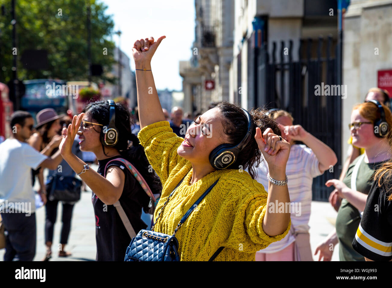Frau mit Kopfhörer über Gesang bei einer Silent Disco Tour in London, Großbritannien Stockfoto