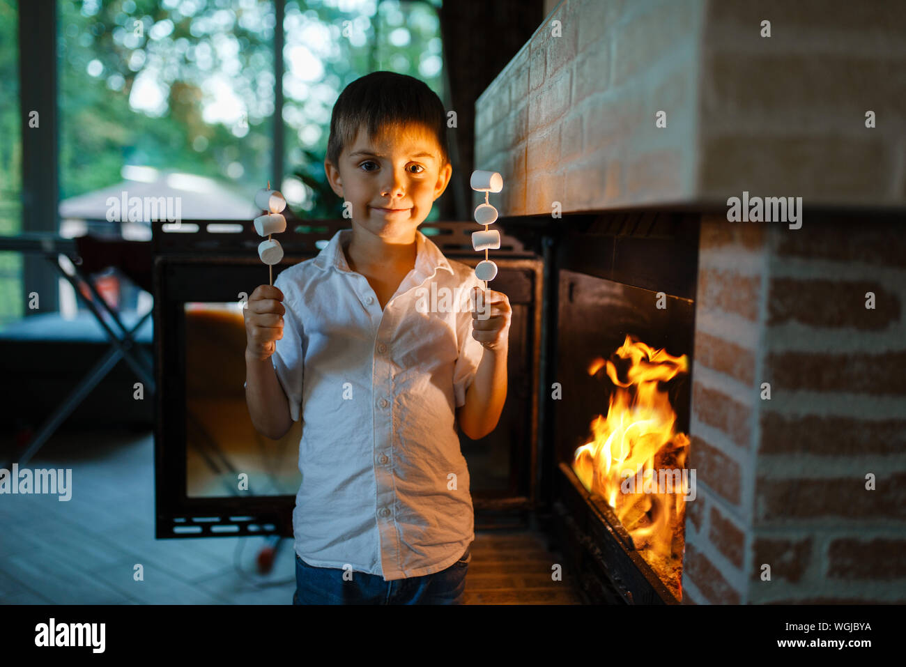 Little Boy braten Würstchen auf Stick am Kamin Stockfoto