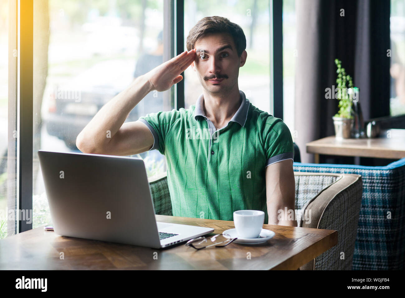 Yes Sir! Junge schwere Geschäftsmann in grünem t-shirt saßen und an der Kamera mit Grüßen Geste und bereit, die Mission abzuschließen. Business conc Stockfoto