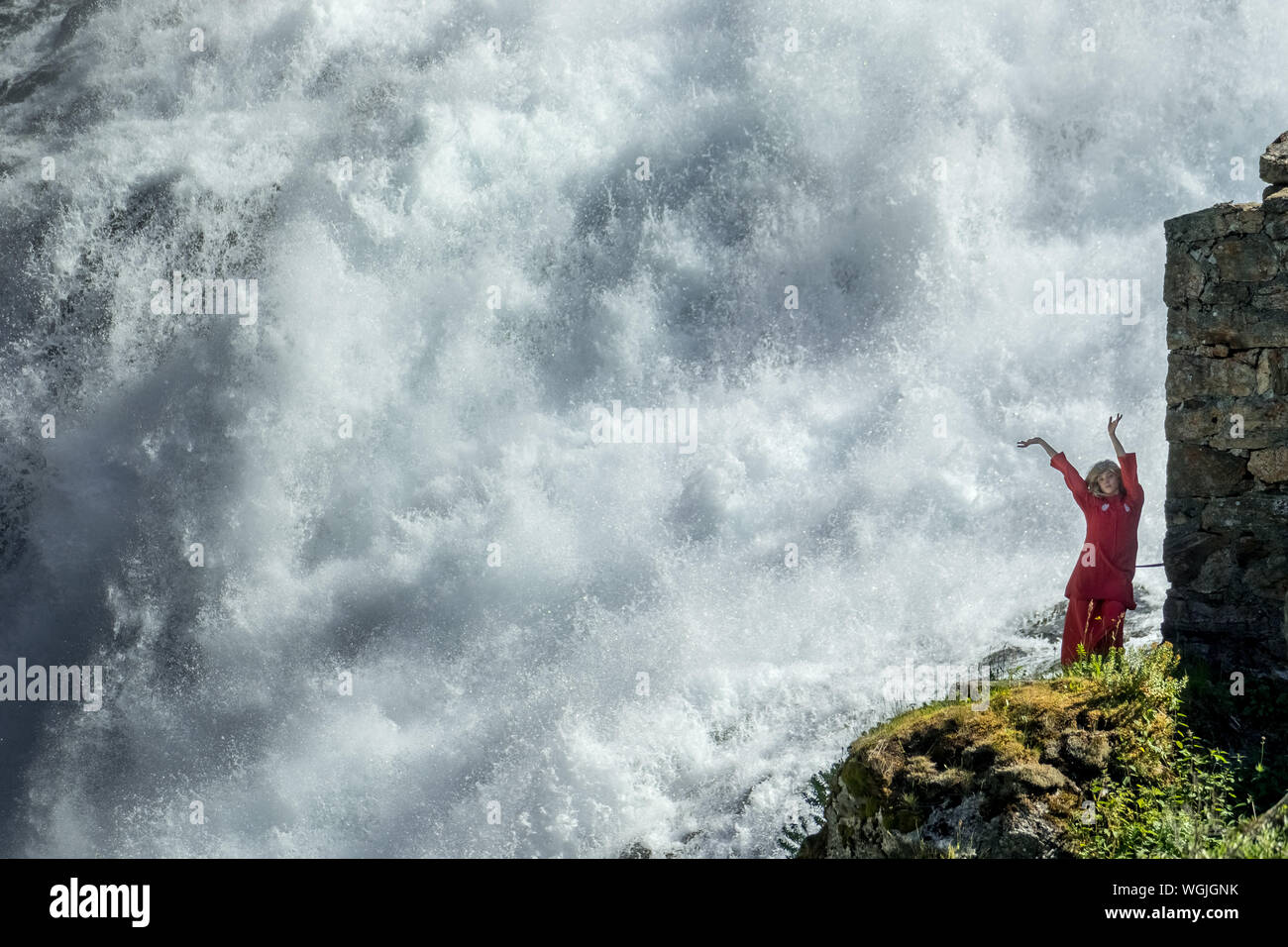 Rot gekleidete Frau ist eine Huldra, Märchen, Saga, Wasserfall Kjosfossen, Wasserfall in der Nähe von Fureberget, Tänzerin im roten Kleid, Felswände, Flåm, Sogn og Fjo Stockfoto