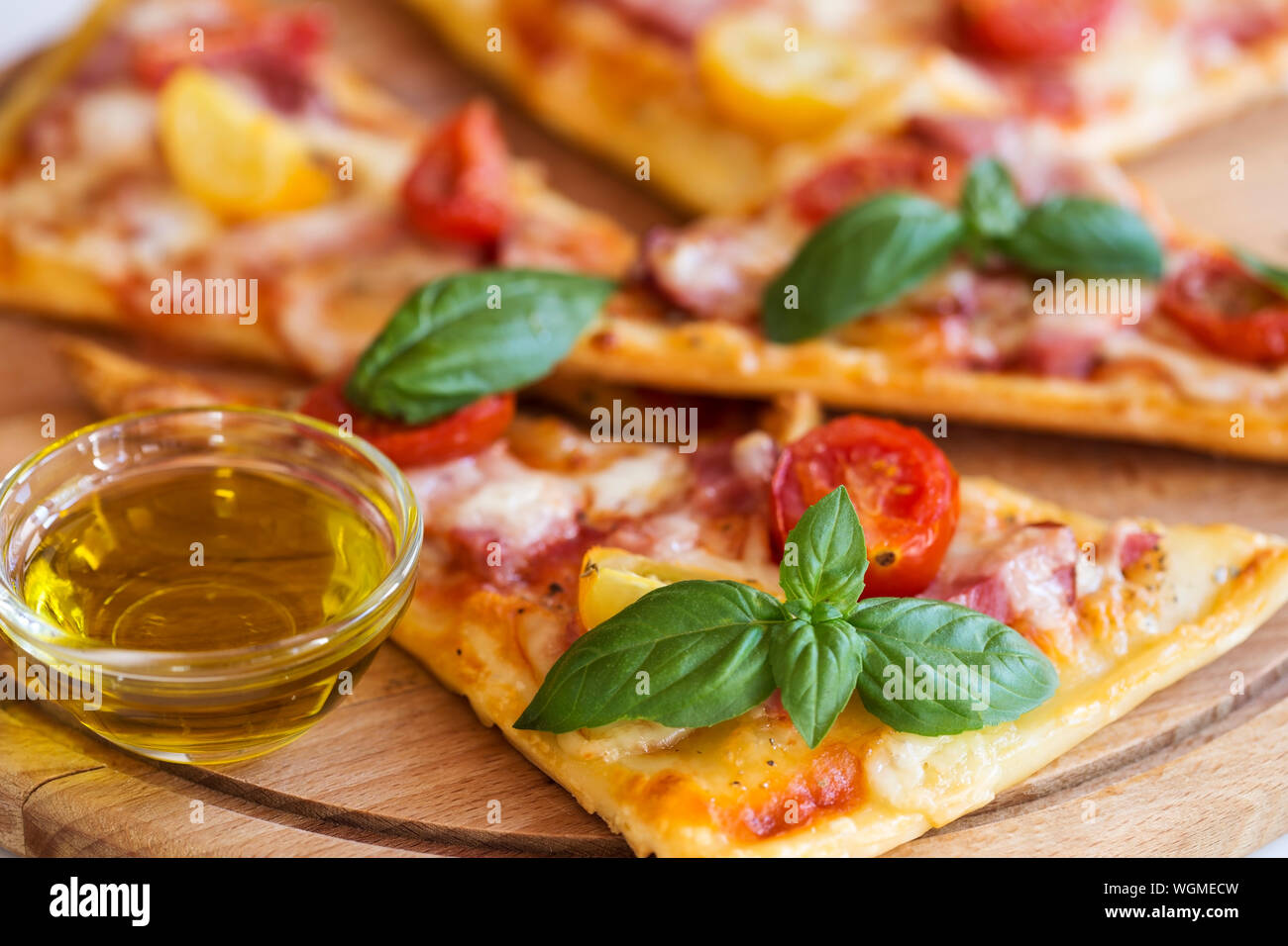 Pizza Scheiben mit Basilikum und Olivenöl auf Holzplatte Stockfoto