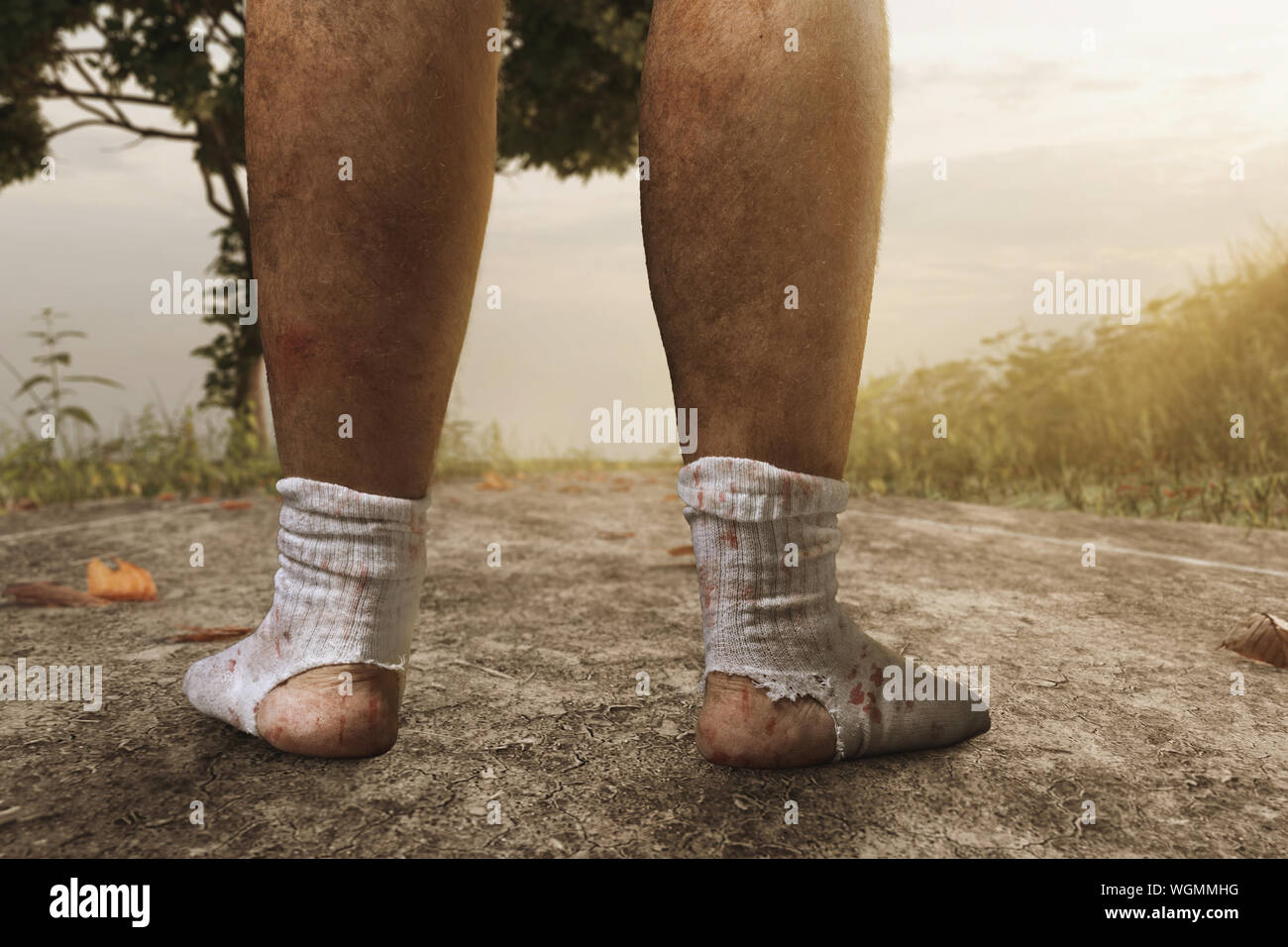 Zurück der schmutzigen, blutigen Füße mit weißen Socken und ein großes Loch auf der Weg in den Abend Sonnenlicht Stockfoto