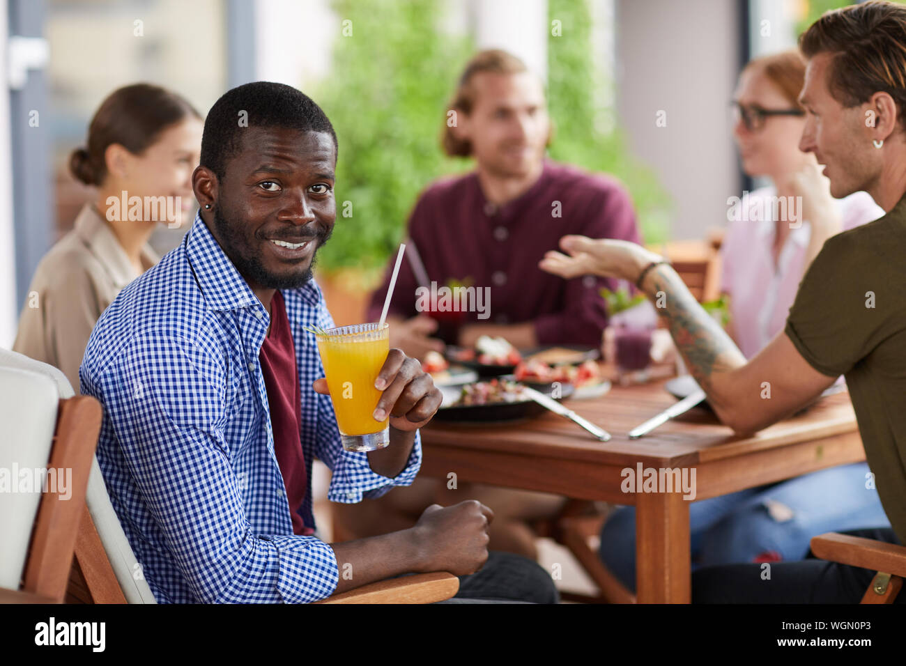 Portrait der afroamerikanischen Mann lächelnd in die Kamera halten Cocktail sitzen am Tisch im Café und genießen Party mit Freunden essen, kopieren Raum Stockfoto
