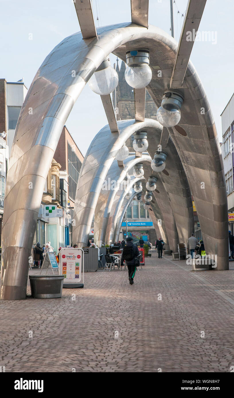 Person zu Fuß die Straße unter moderne futuristischen Edelstahl Projektion Beleuchtung Bögen in Blackpool, Lancashire, England, Großbritannien Stockfoto