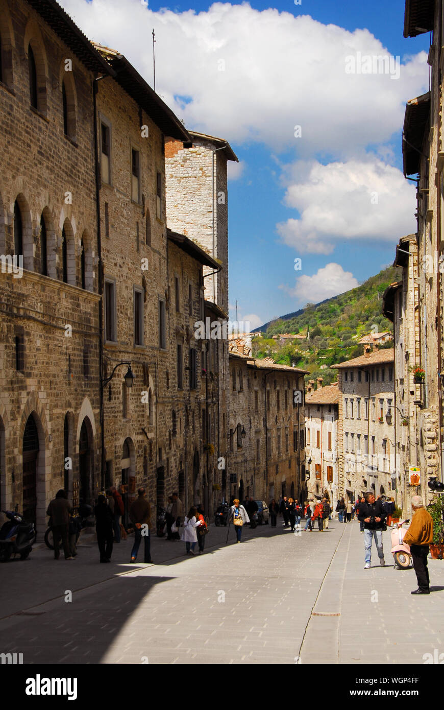 Touristen zu Fuß entlang der Via dei Consoli (Straße der Konsuln), der wichtigsten Einkaufsstraße in der mittelalterlichen Altstadt von Gubbio Stockfoto