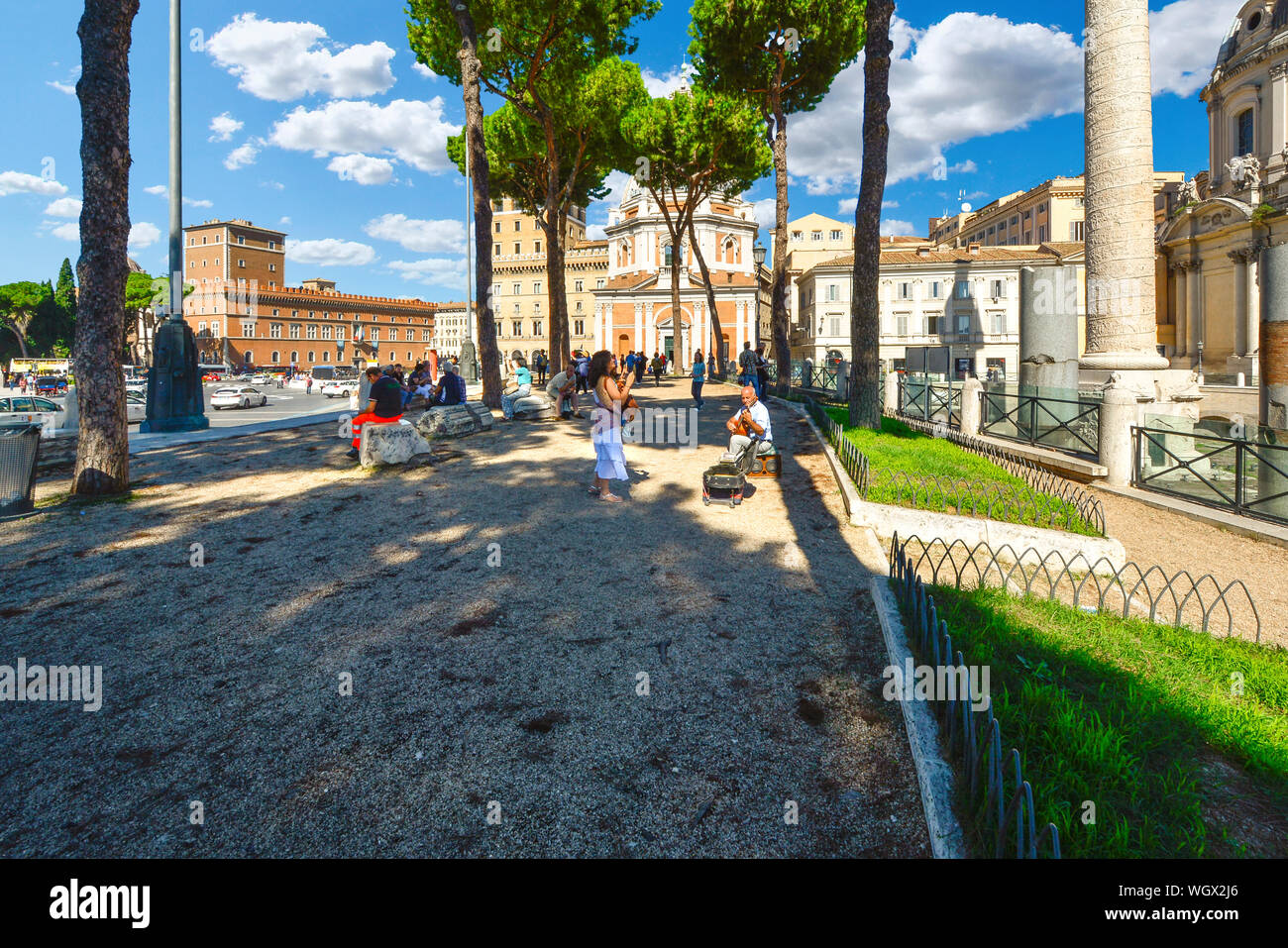 Eine Frau hört auf einer Straße oder Musiker, Gaukler, wie er Gitarre vor der antiken Forum Romanum in Rom, Italien spielt Stockfoto