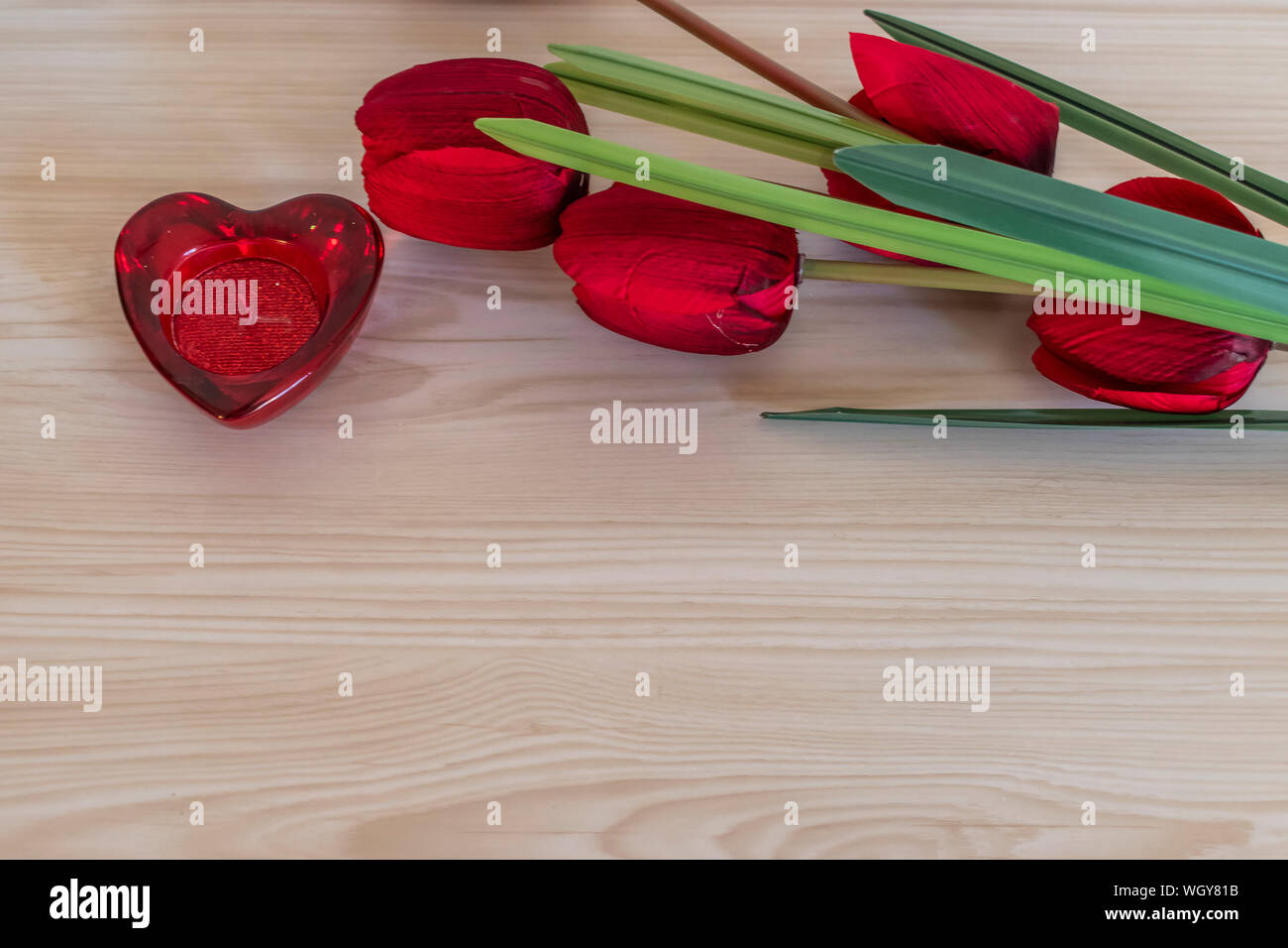 Tulip Blumen und herzförmige Kerze auf einem Holz Textur Hintergrund. Valentinstag Konzept. Stockfoto