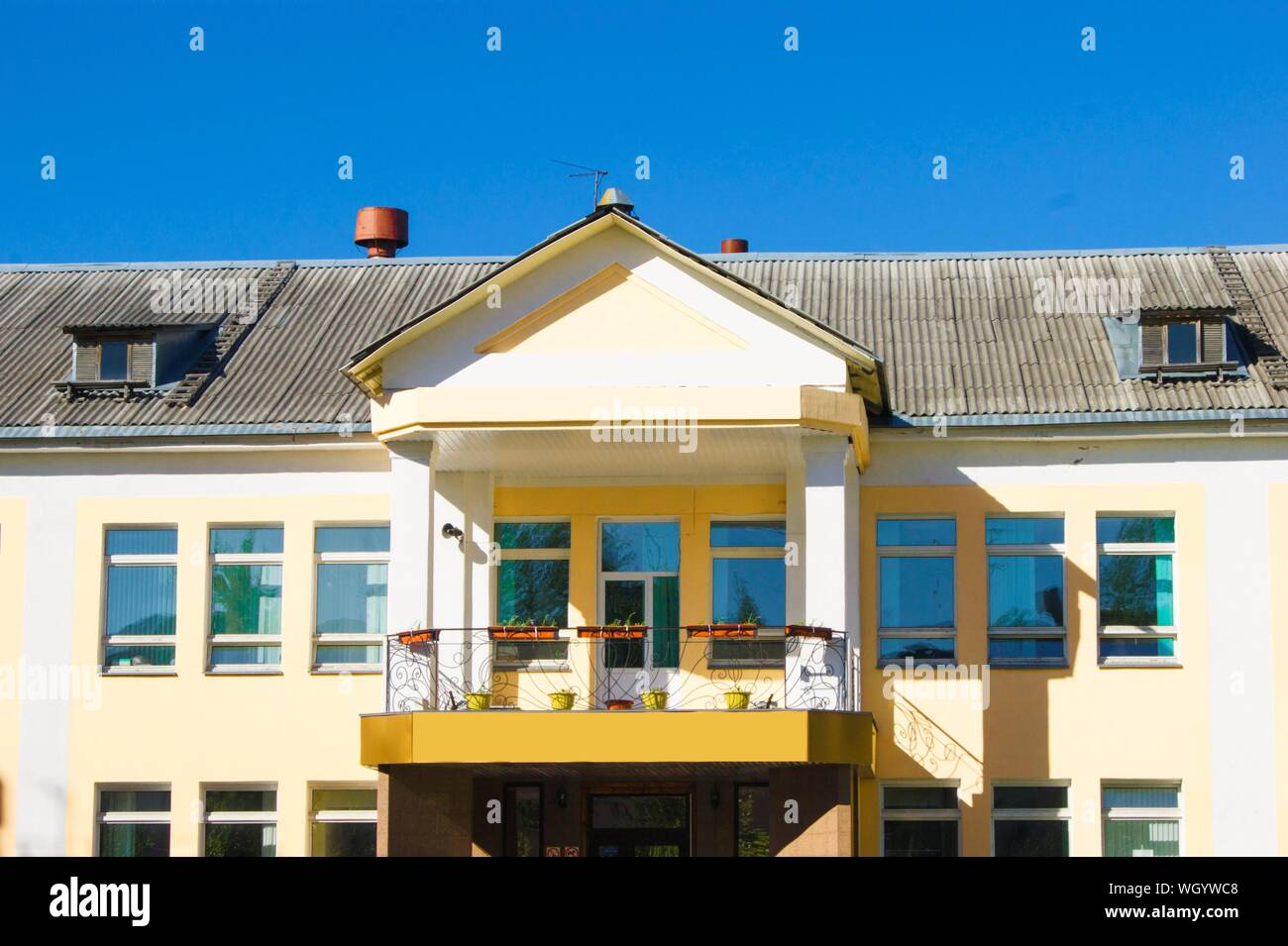 Elemente der städtischen Park Architektur, Licht gelbes Gebäude gegen den blauen Himmel - Dach, Fenster, Balkon Stockfoto