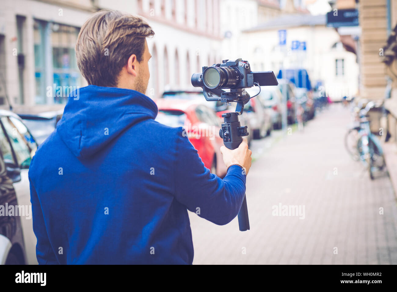 Stattliche Einflussnehmer Vlogger machen Video mit spiegellosen Kamera und Gimbal in der Stadt Stockfoto