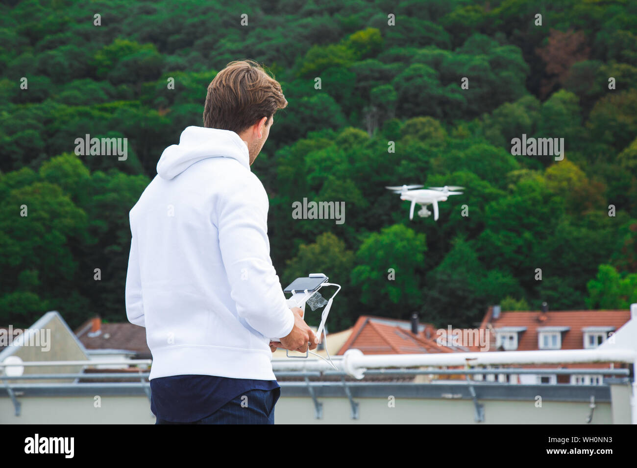 Hübscher junger Erwachsener Mann Fliegen mit dem Brummen auf dem öffentlichen Dach Neben der Wald Stockfoto