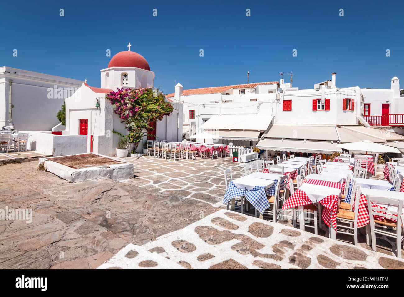 Kleines Quadrat mit der griechischen Kirche und Restaurants in der Altstadt von Mykonos, Griechenland. Stockfoto
