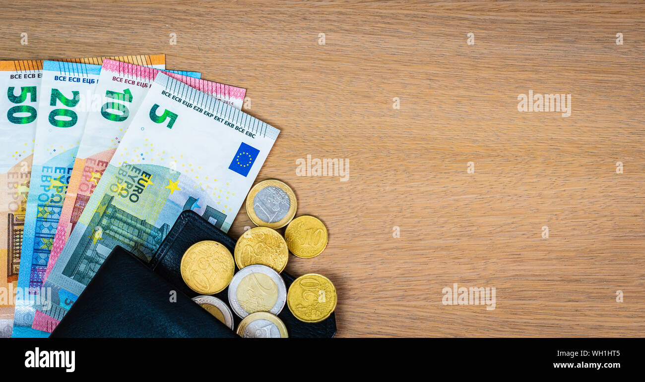 Europäische Banknoten und Münzen in schwarzem Leder Brieftasche auf Holz- Hintergrund. Euro Geld. Stockfoto