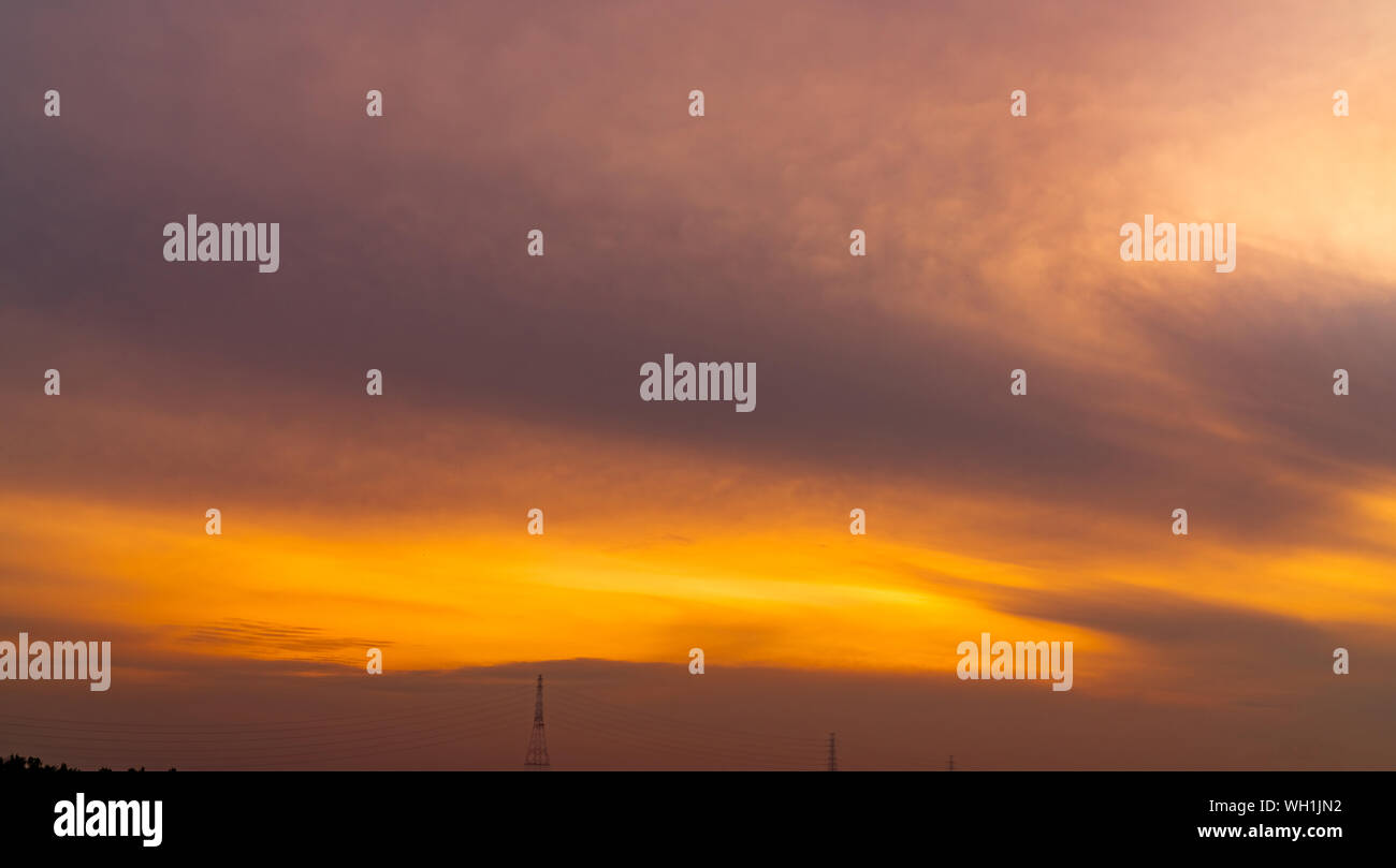 Golden Sunset Himmel über hohe Spannung elektrische Tower. Golden Himmel und weißen Wolken. Schöne cloudscape. Natur Hintergrund. Leitungen. Friedliche Stockfoto