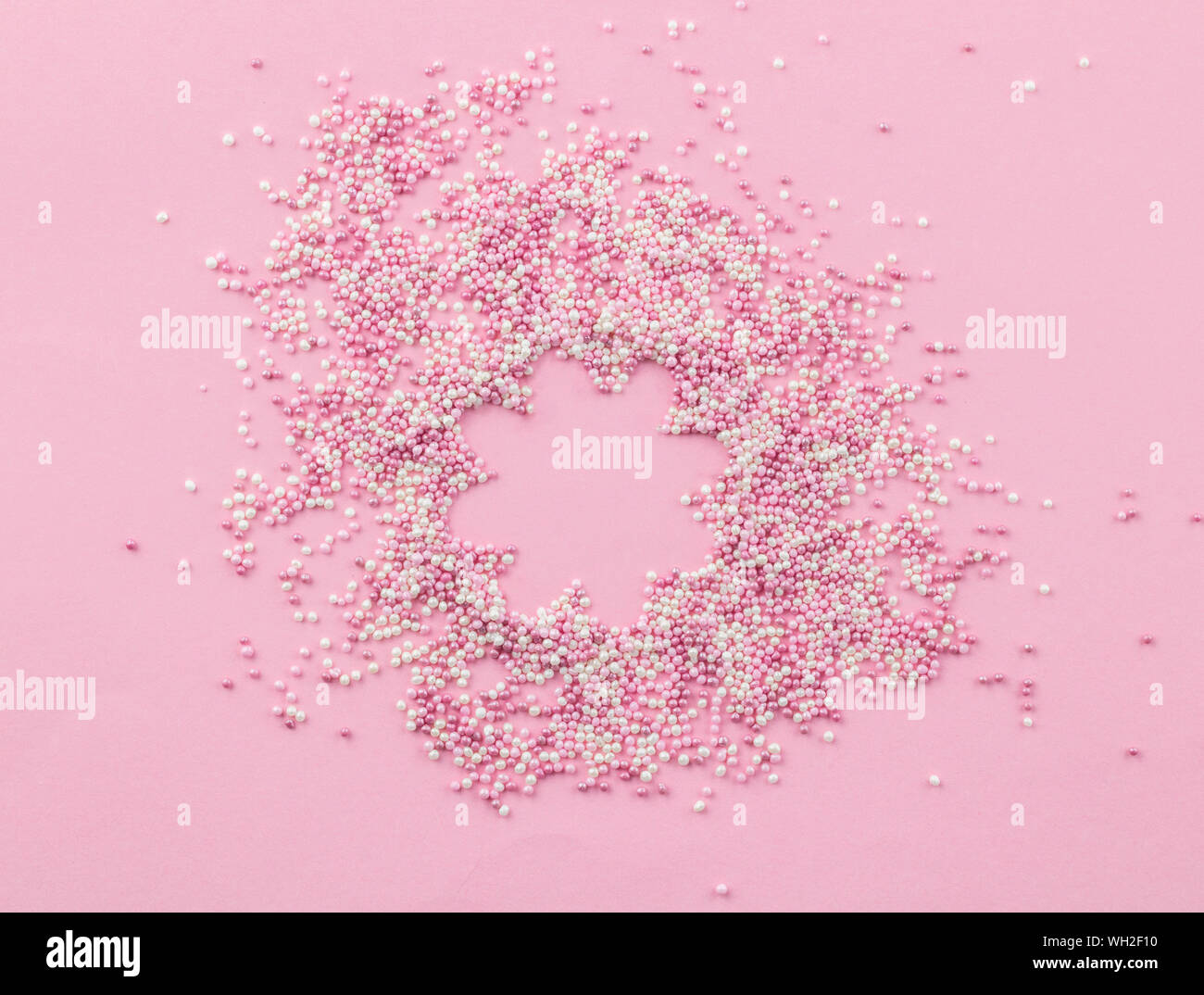 Rosa und weissen essbaren pearlized Streusel auf rosa Hintergrund - Kuchen topping Pearly pink mit Blume kopieren Platz im Zentrum besprüht Draufsicht phot Stockfoto