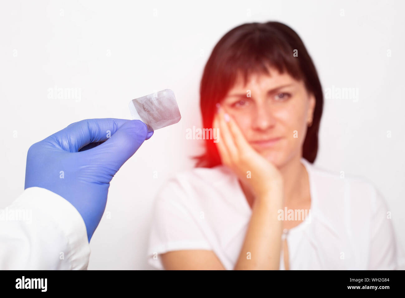 Ein Zahnarzt Arzt hält einen x-ray von einem Patienten mit einer Pulpitis eines Zahnes vor dem Hintergrund eines Mädchens, hat Schmerzen und Entzündungen der Zahn Stockfoto