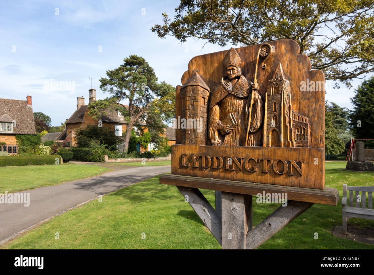 Village Green und verzierten Eichenholz geschnitzte Ortsschild, Kirche und Turm, Lyddington, Rutland, England, Großbritannien Stockfoto