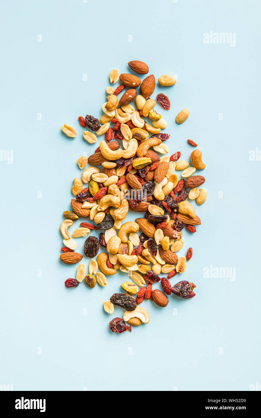 Mix aus verschiedenen Nüssen und Rosinen auf blauem Hintergrund. Ansicht von oben. Stockfoto