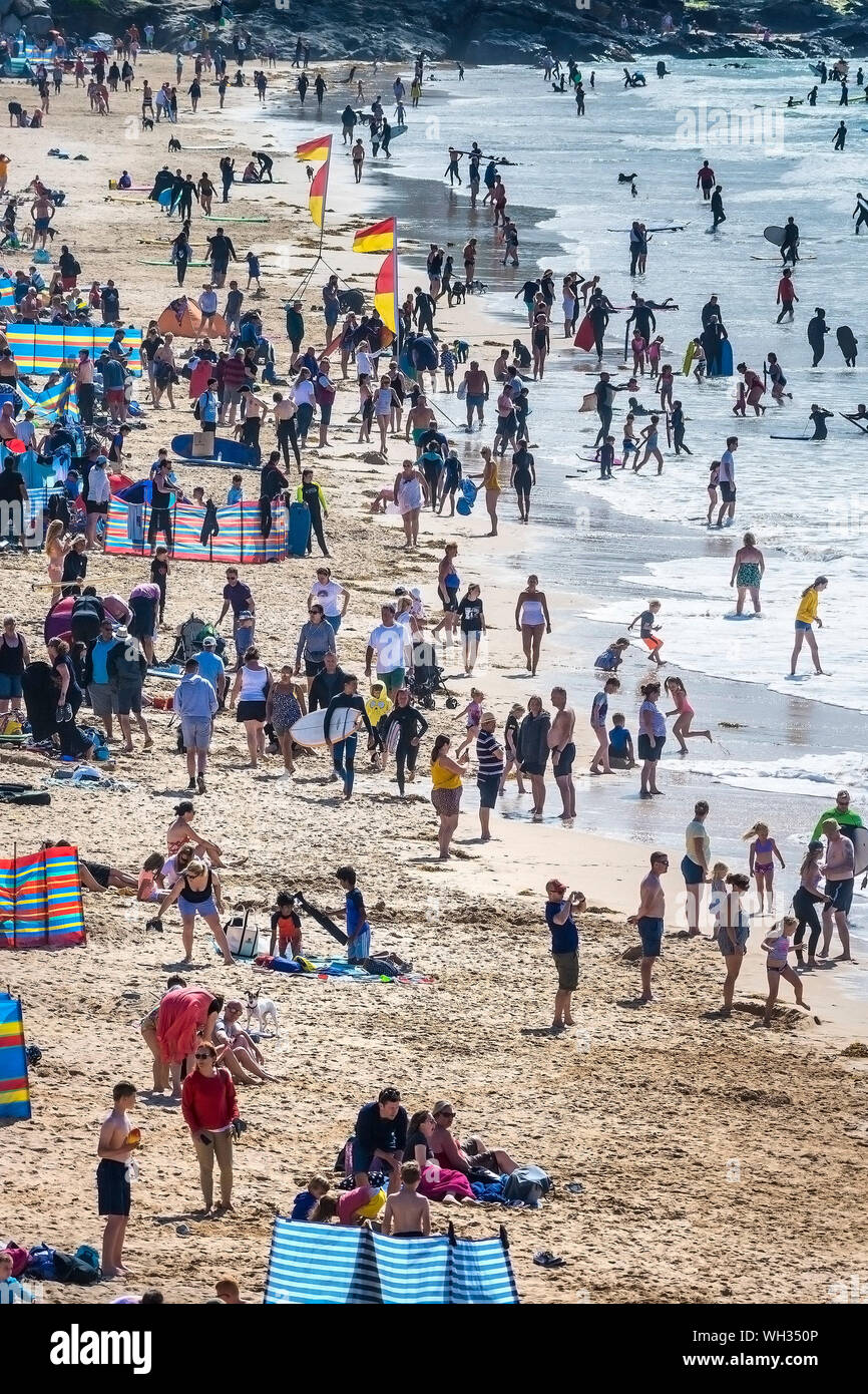 Urlauber verbringen ihren Urlaub an einem sonnigen und überfüllten Fistral Beach in Newquay in Cornwall. Stockfoto
