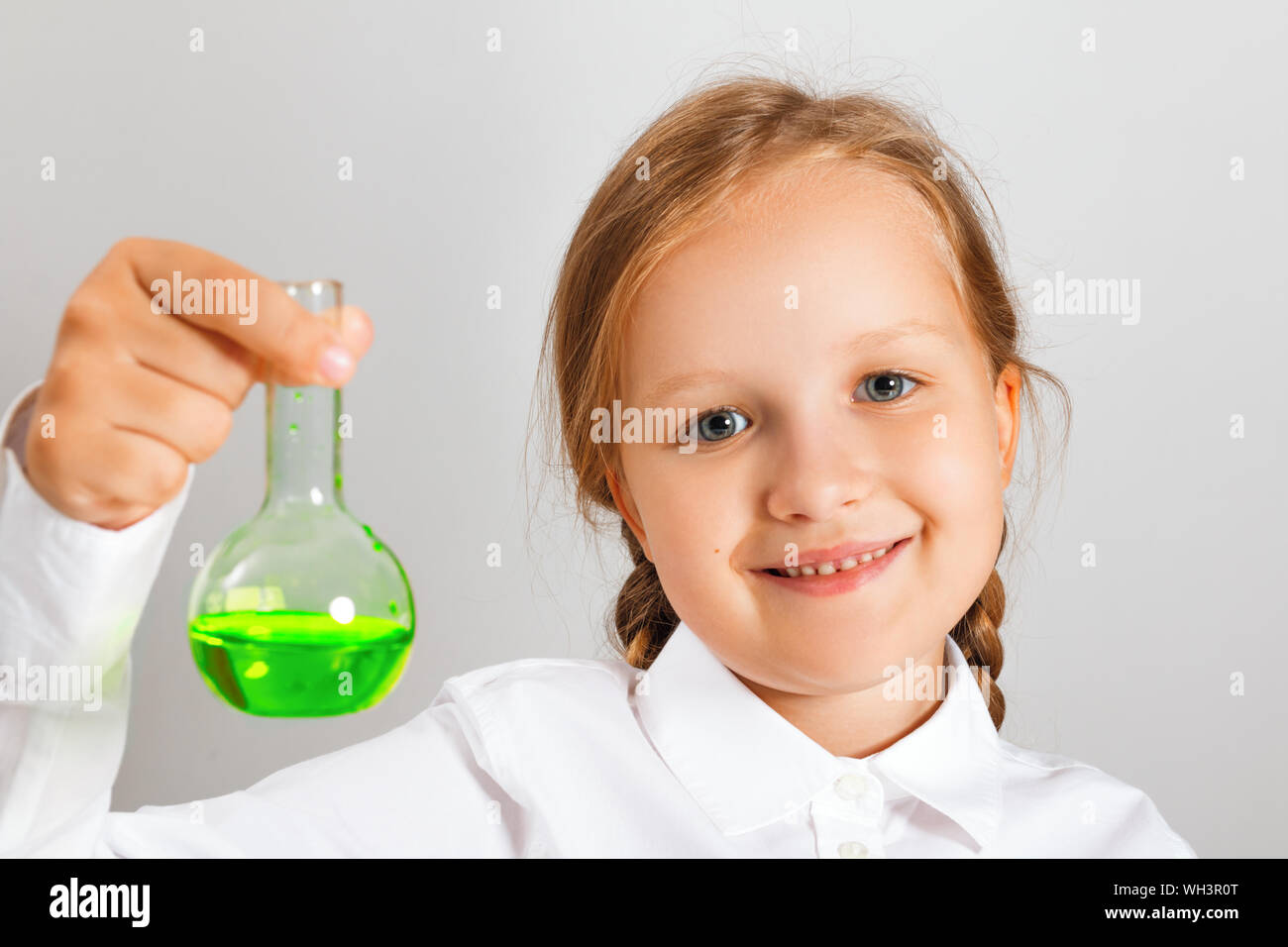Kleines Mädchen Student hält in seiner Hand ein Gefäß mit einer Flüssigkeit und sieht in die Kamera. Ein Kind ist die Durchführung einer chemischen Experiment. Stockfoto