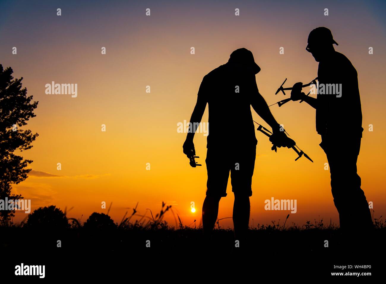 Zwei Personen mit Drohnen zu entspannenden Flug mit ihren Flugzeugen während der malerischen Sonnenuntergang. Antenne Technologien. Stockfoto