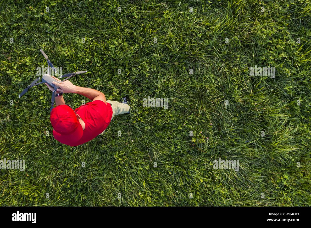 Kaukasischen Männern in seinem 30s mit einer Drohne ein Mitten in der Wiese. Foto von oben genommen. Stockfoto