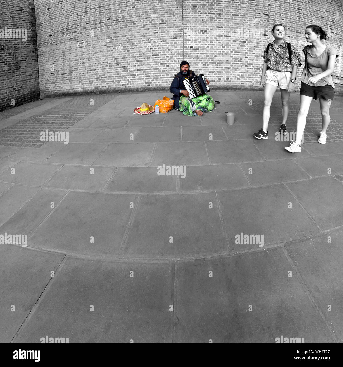 London, England, UK. Zwei Mädchen zu Fuß hinter einem Gaukler spielen auf dem Akkordeon, in Southwark Stockfoto