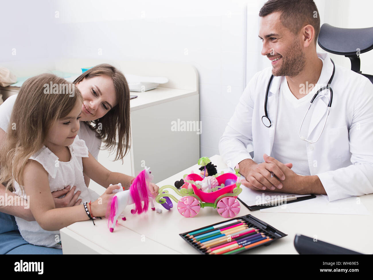 Positiven pädiatrischen Arzt während der Arbeit mit einem Kind, die Mutter mit einem Kind von einem Kinderarzt untersucht Stockfoto