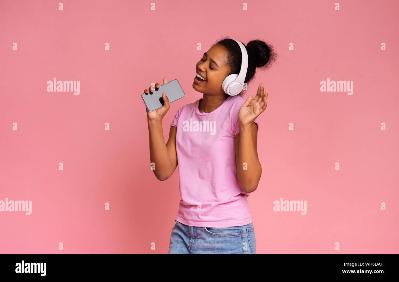 Happy african american teen Singen in Smartphone wie Mikrofon Stockfoto