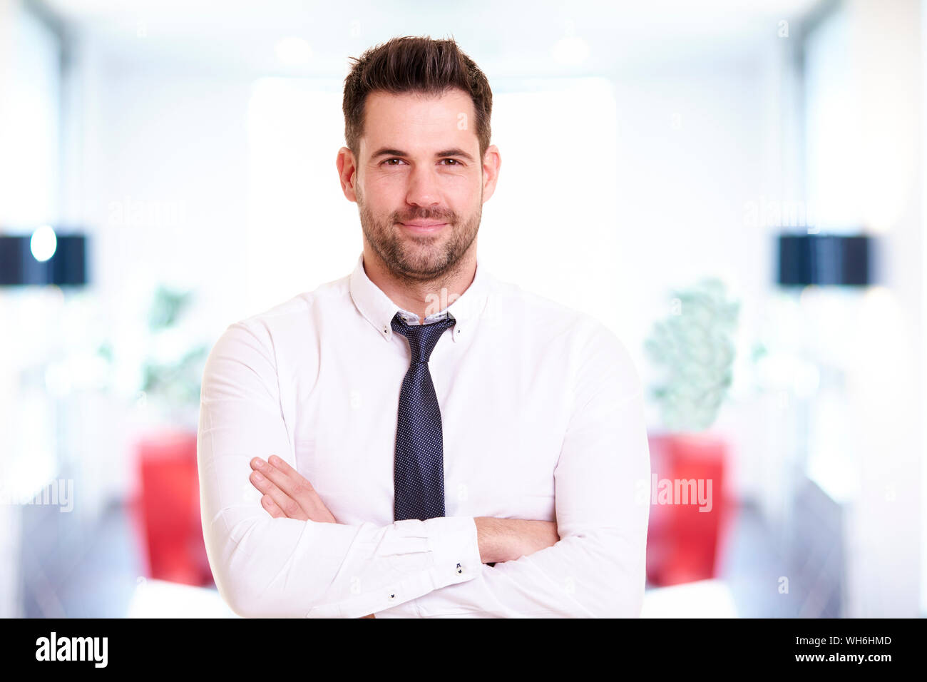 Portraitfotos von lächelnden Geschäftsmann mit Hemd und Krawatte beim Stehen im Büro und lächelnd. Stockfoto