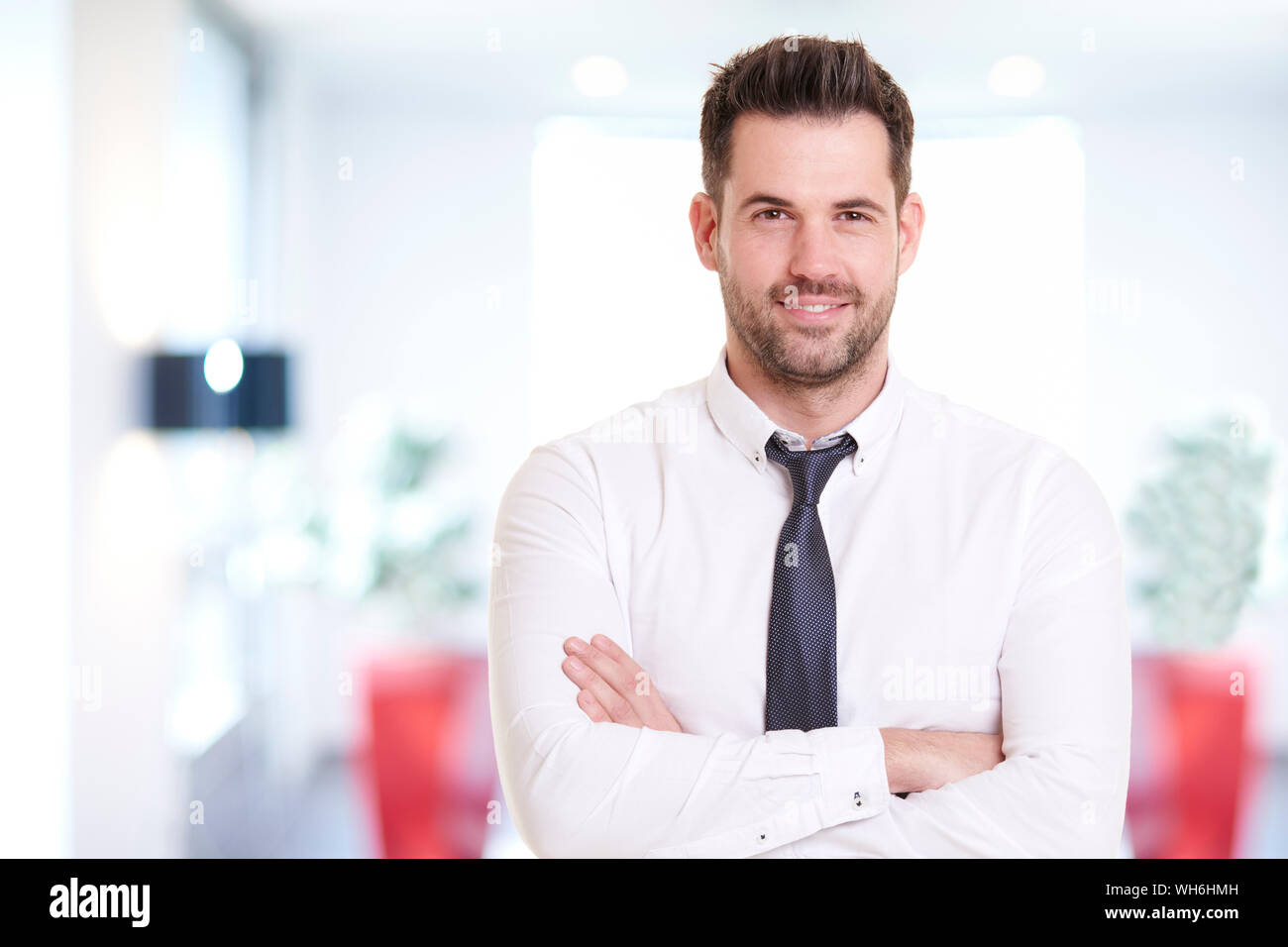 Portraitfotos von lächelnden Geschäftsmann mit Hemd und Krawatte beim Stehen im Büro und lächelnd. Stockfoto