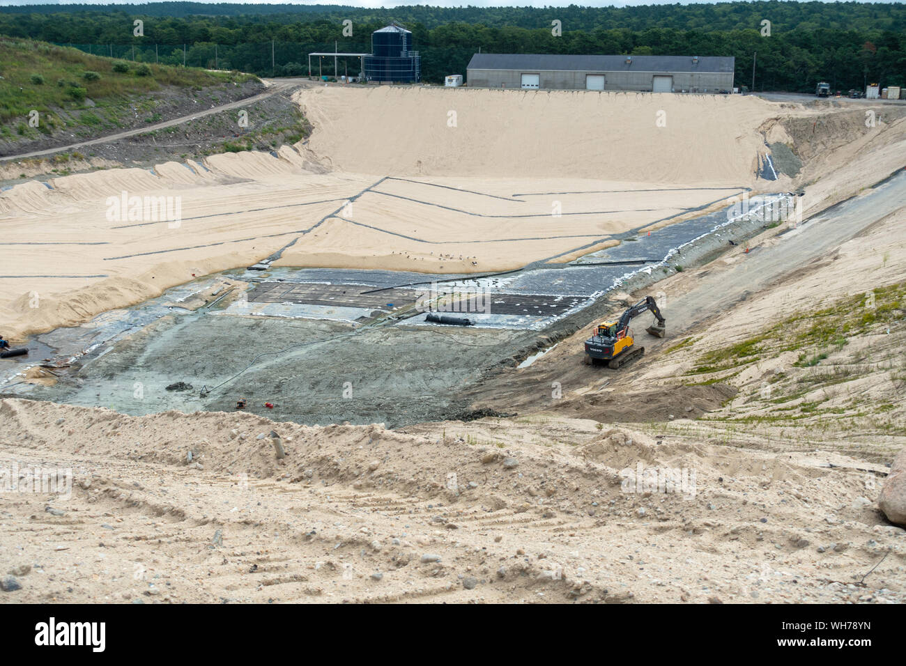 Ein Volvo Baggerlader sitzt an der Unterseite eines im Bau Deponierung Zelle als dammböschungen Ton-passagierschiff ist installiert und mit Sand bedeckt Stockfoto