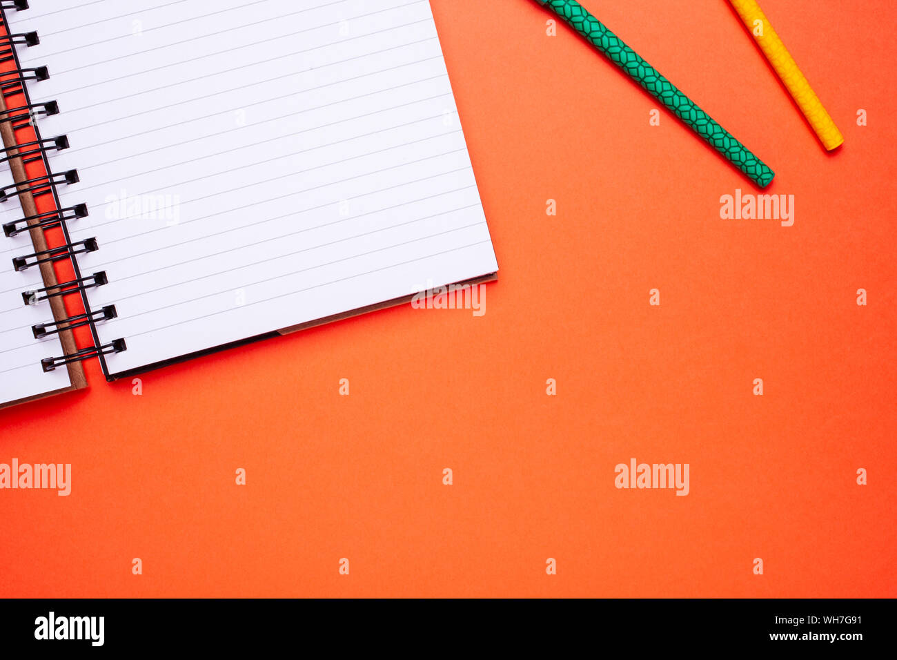 Flach Draufsicht mockup Foto von Arbeitsbereich mit Laptop und Stifte auf orange Pastell Hintergrund. Stockfoto