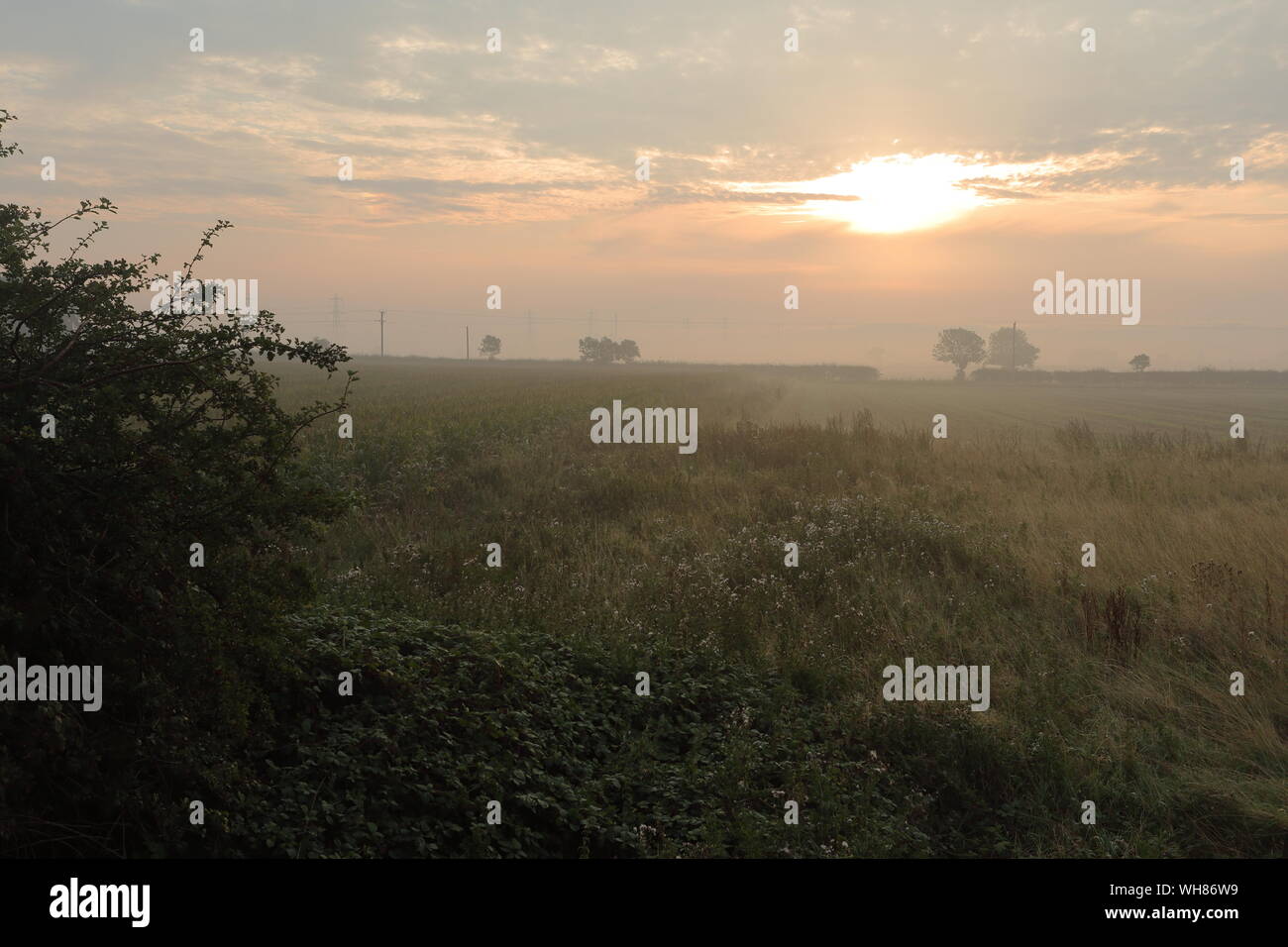 Misty Sonnenaufgang am Winterton mit glühenden Sonne durch die Wolken Stockfoto