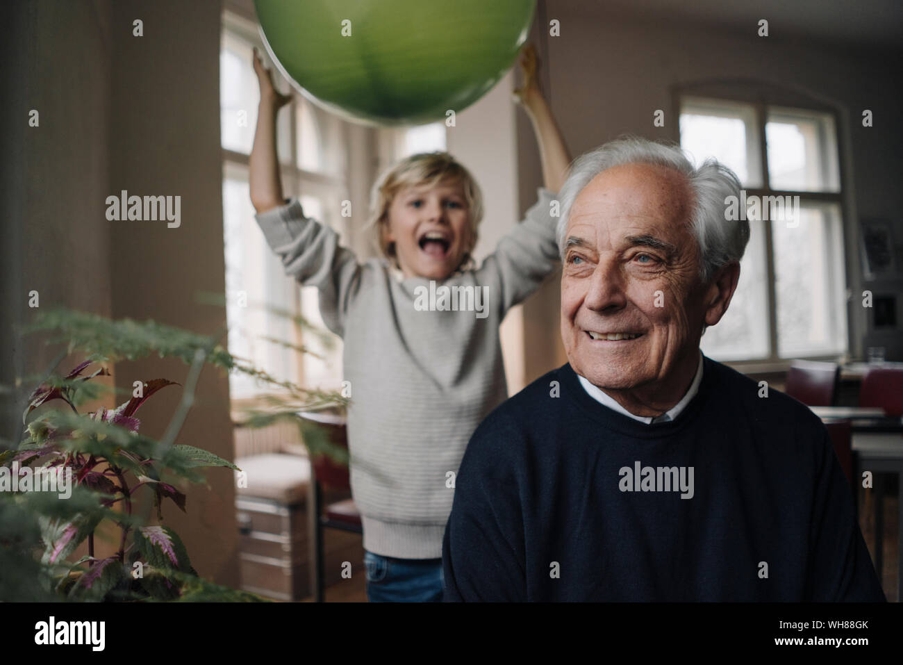 Portrait von lächelnden älteren Mann mit Enkel holding Ballon im Hintergrund Stockfoto