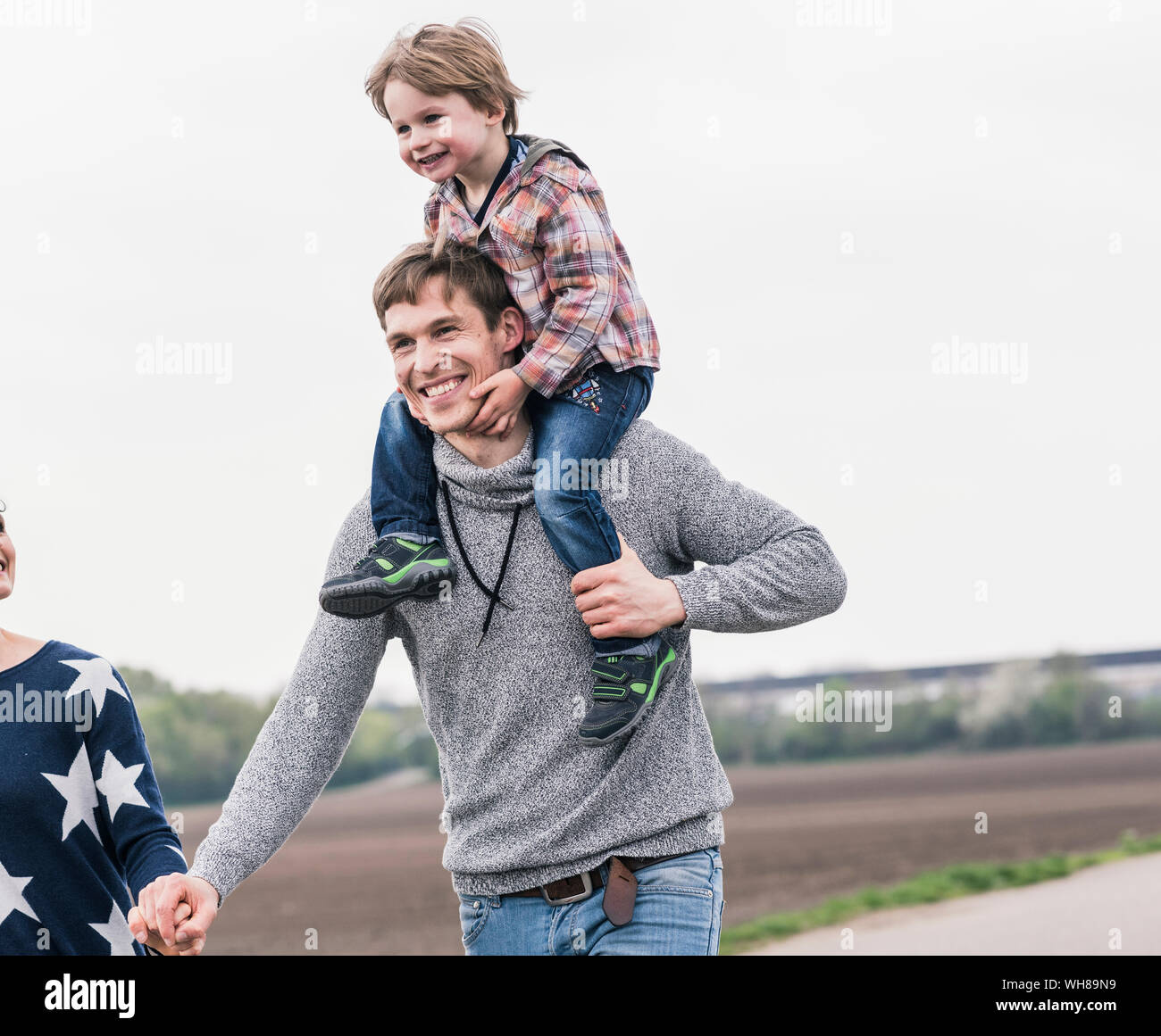 Glückliche Familie zusammen zu Fuß neben Feldern, Vater mit Sohn piggyback Stockfoto