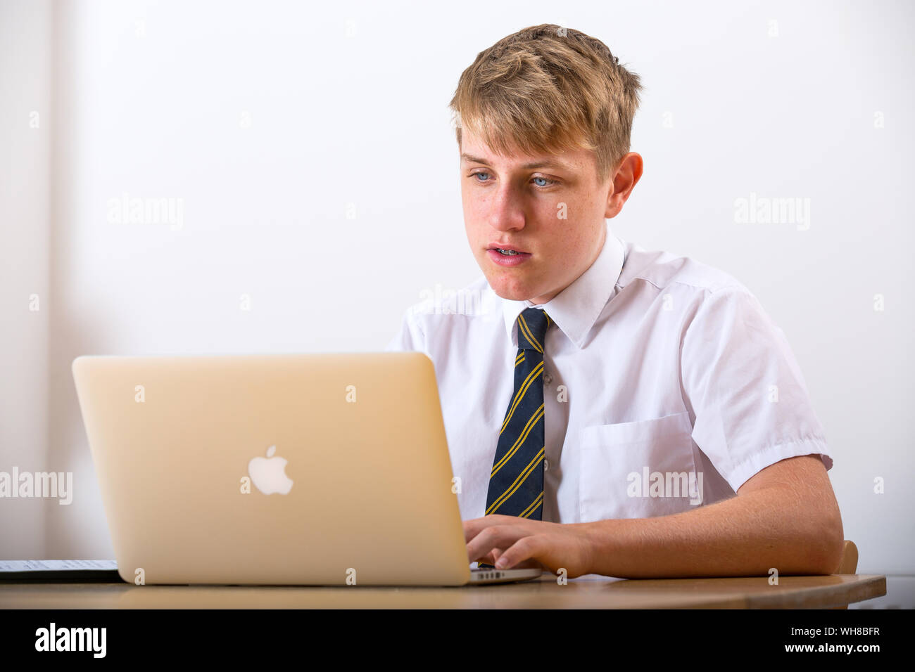 Ein Teenager Schule Junge in Uniform arbeiten auf einem Laptop. Stockfoto