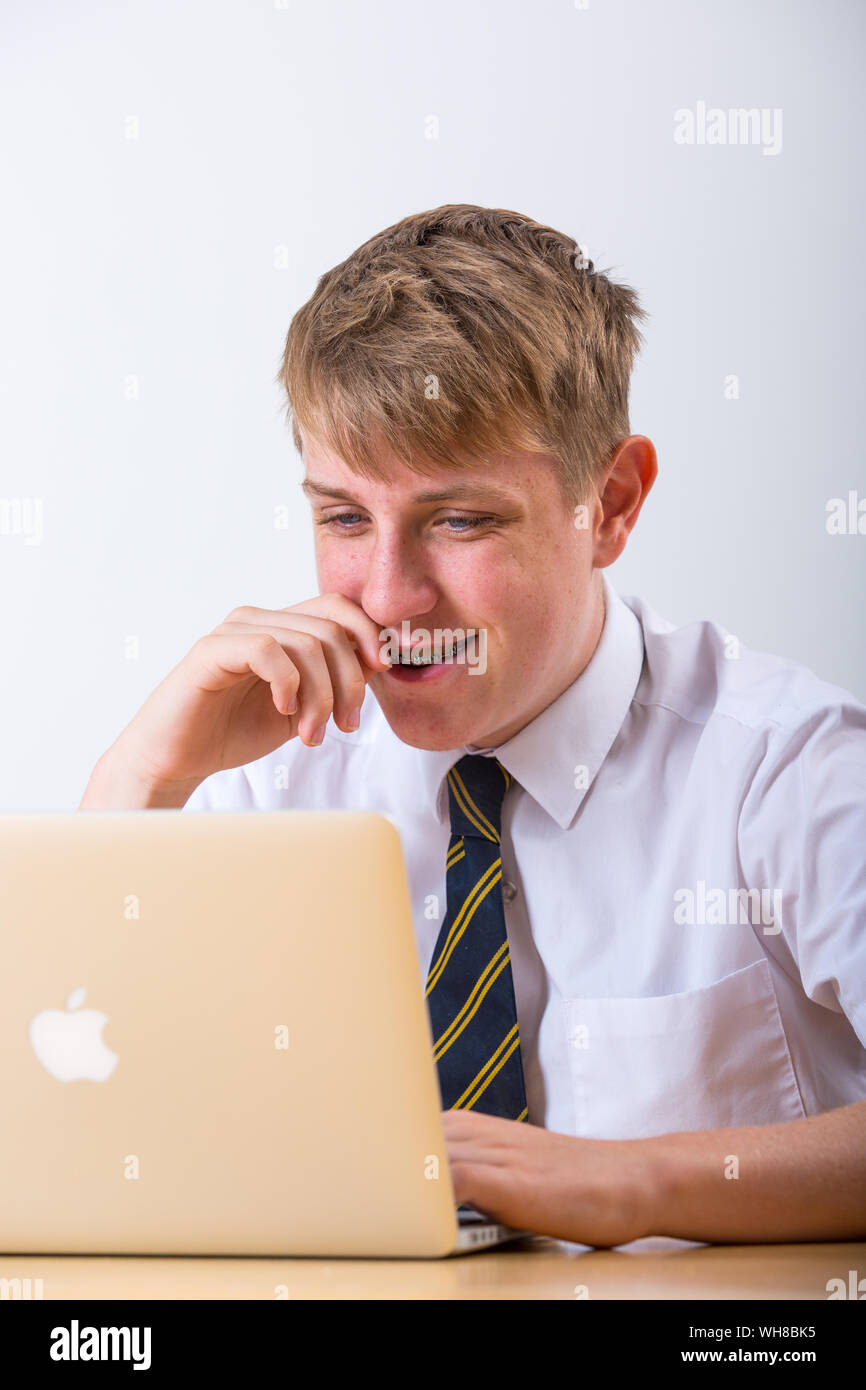 Ein Teenager Schule Junge in Uniform arbeiten auf einem Laptop. Stockfoto