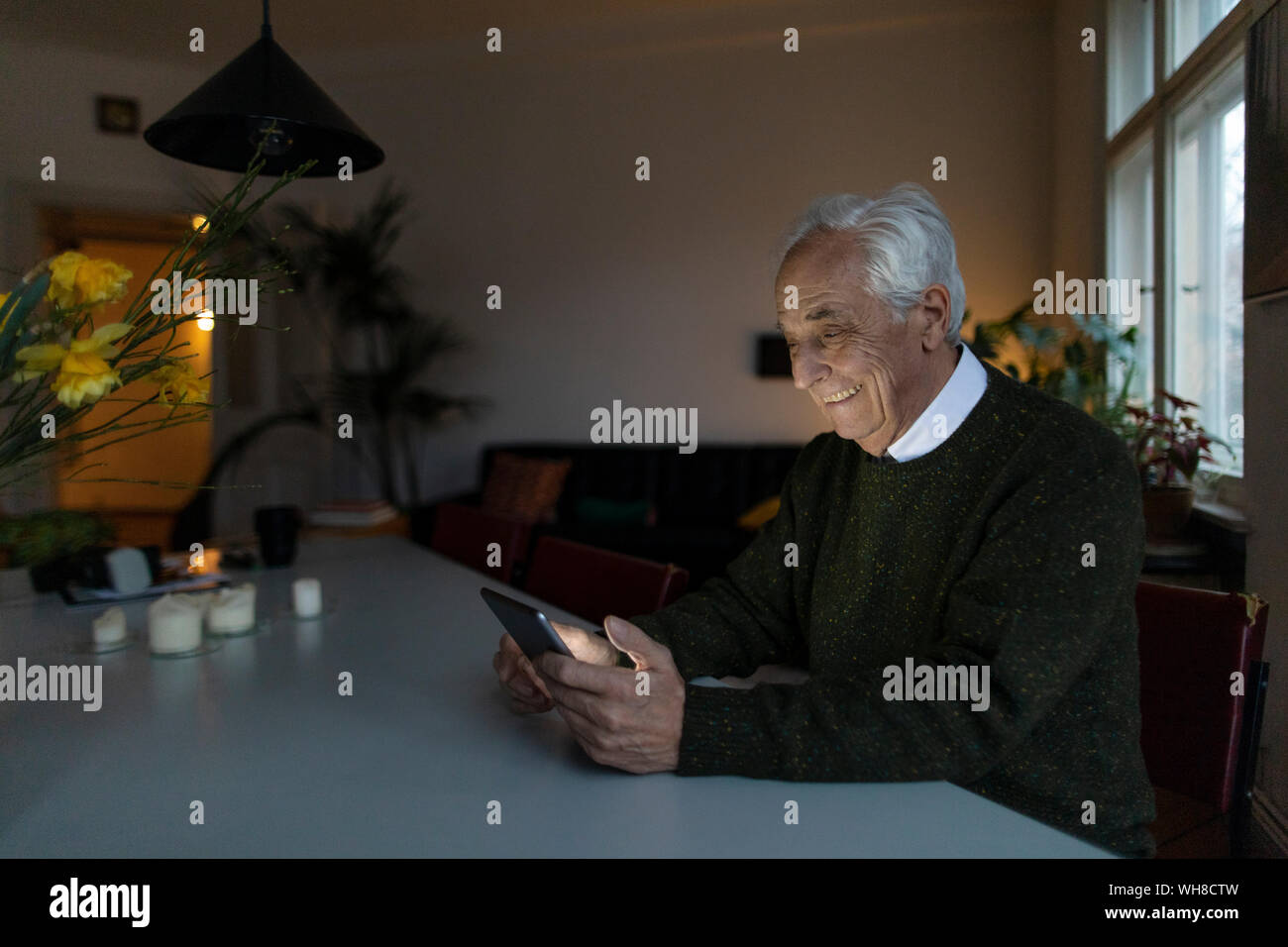 Lächelnd älterer Mann mit Tablette zu Hause Stockfoto