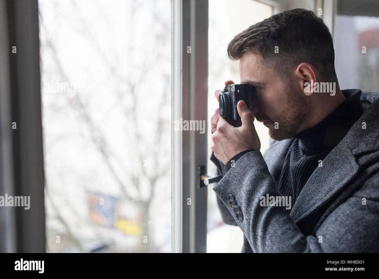 Junger Mann Bilder aufnehmen am Fenster Stockfoto